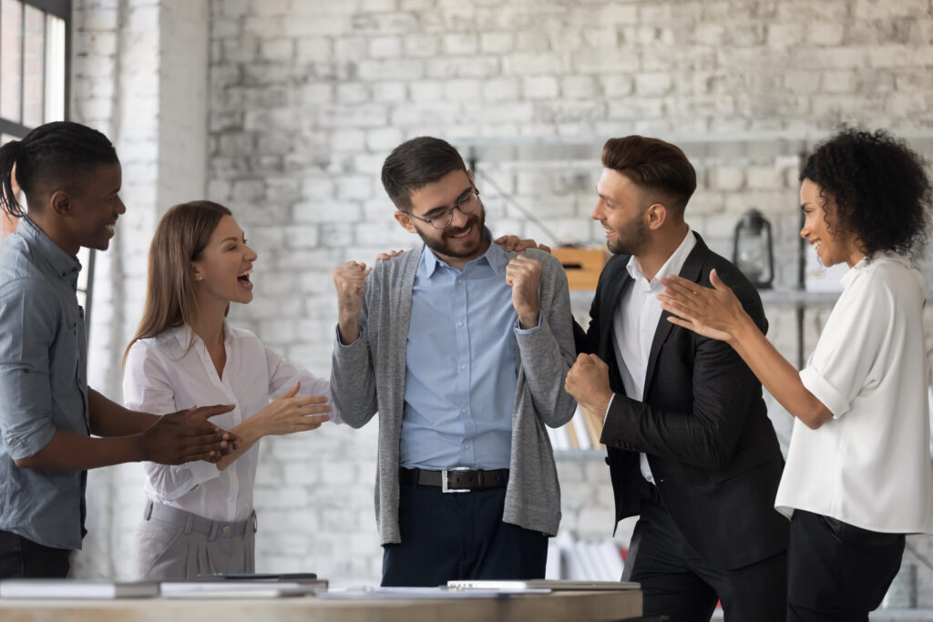 A young business professional being celebrated by his peers in the office.