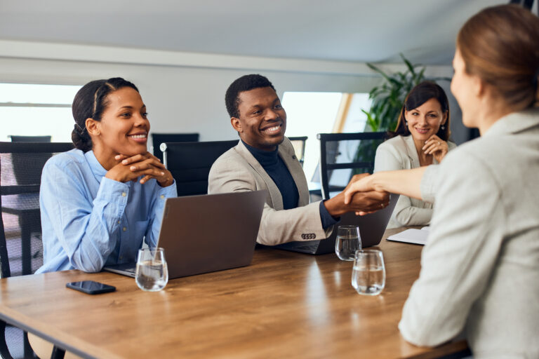 Corporate professionals shaking hands with a potential partner in the boardroom.