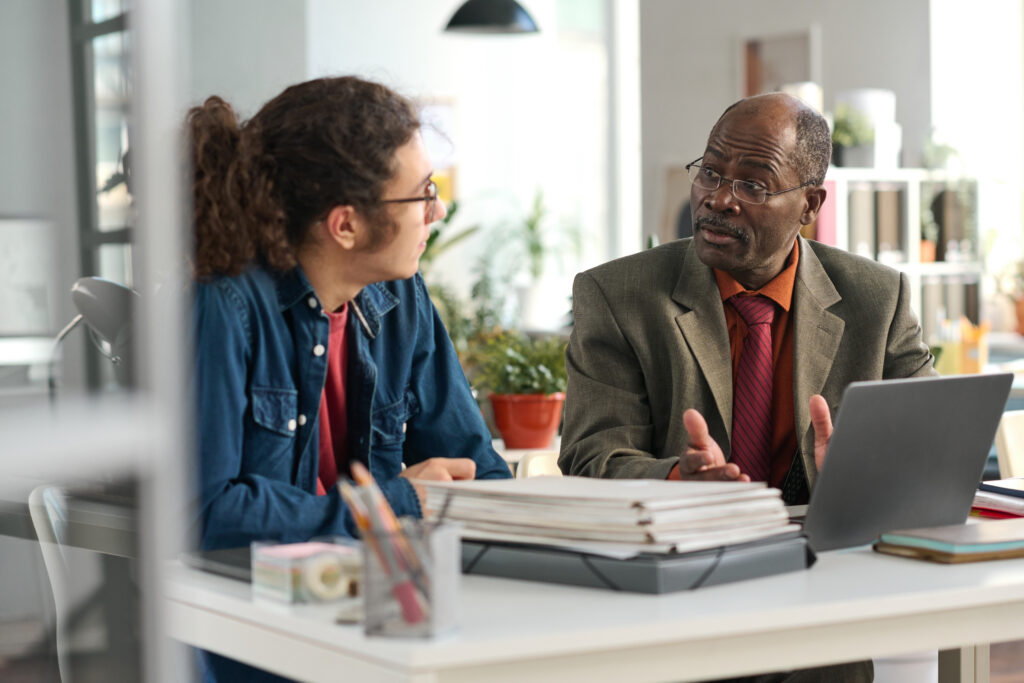 A senior business professional mentoring his younger colleague in an office setting.