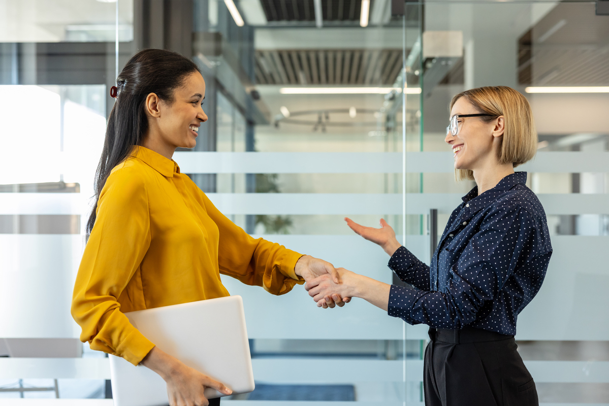 Two business professionals shaking hands in a modern office setting